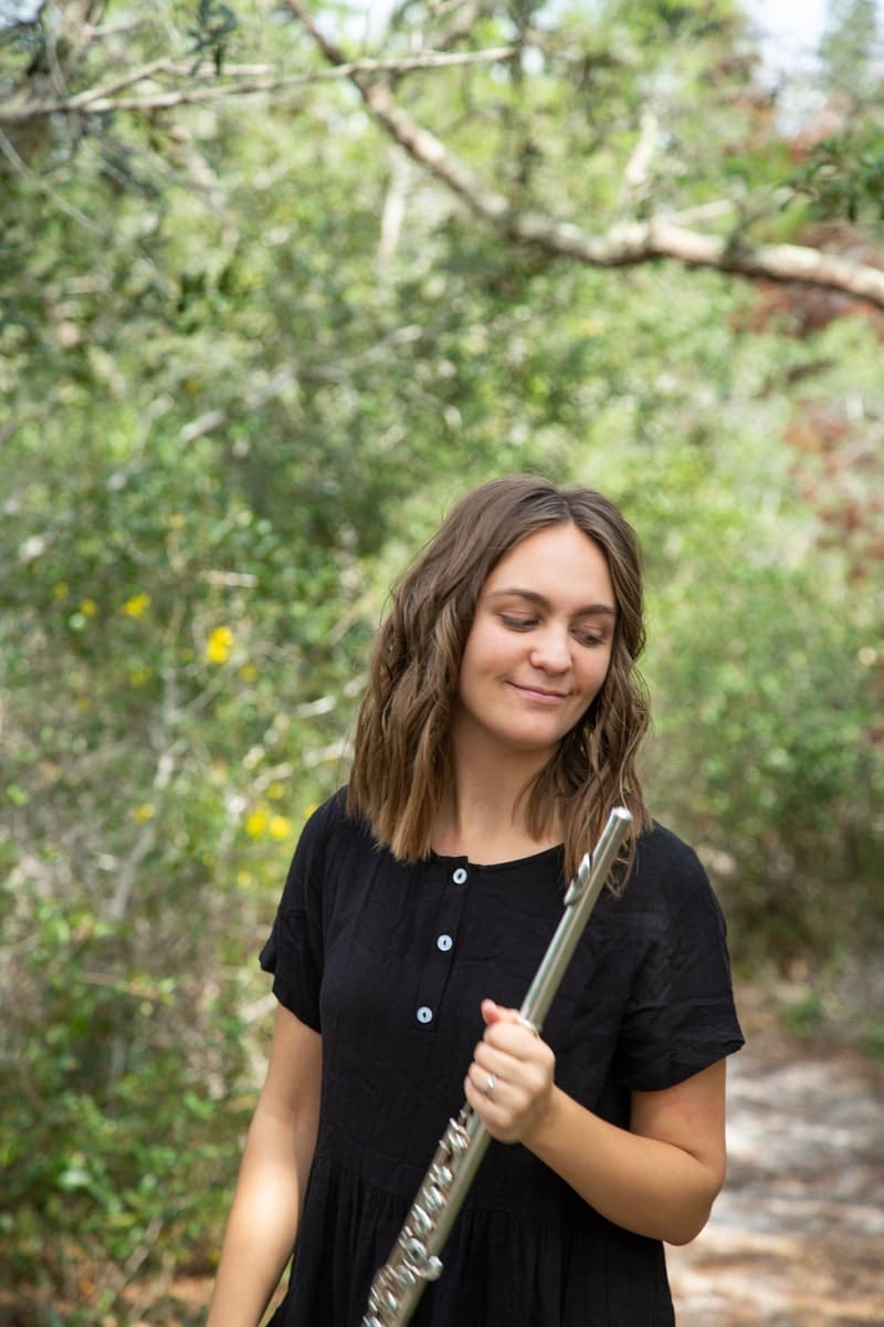 brenna holding flute in woods